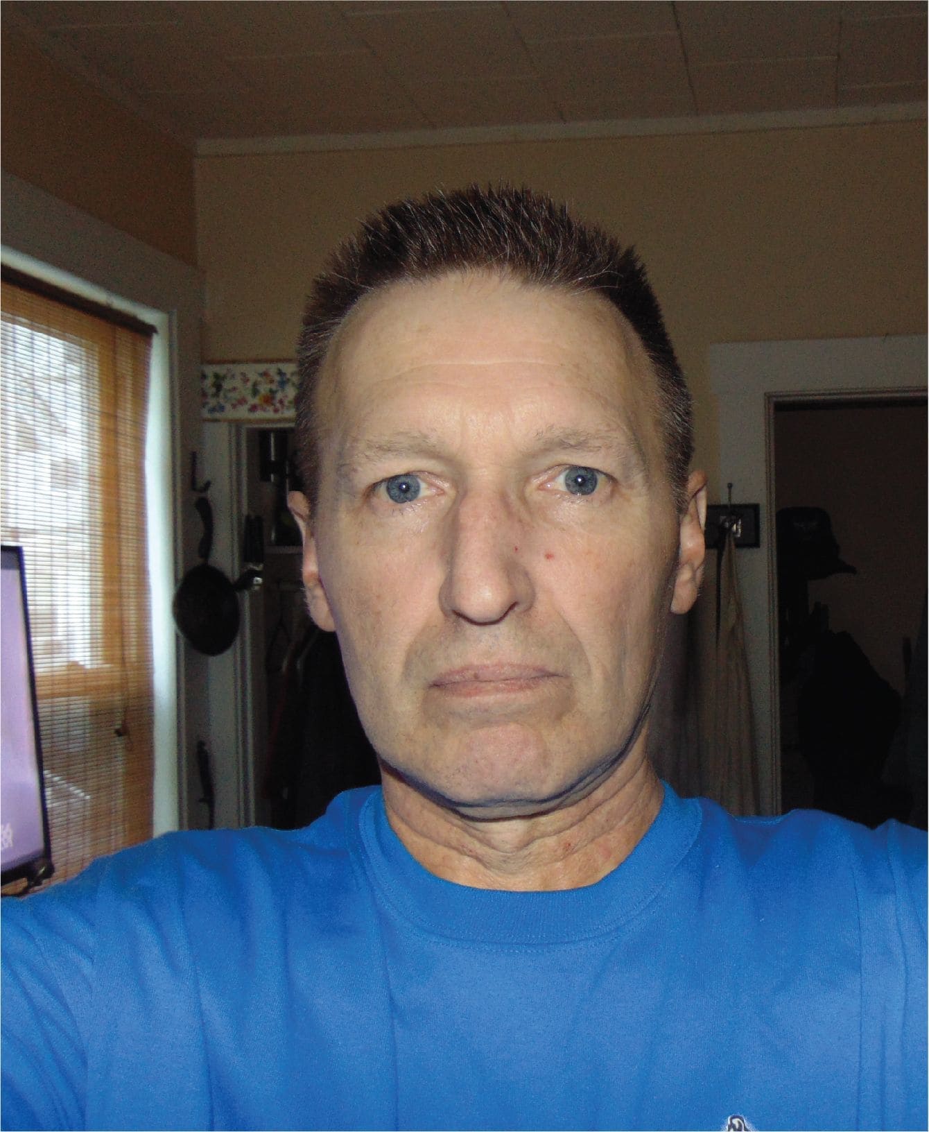 A man wearing a blue shirt, standing confidently.
